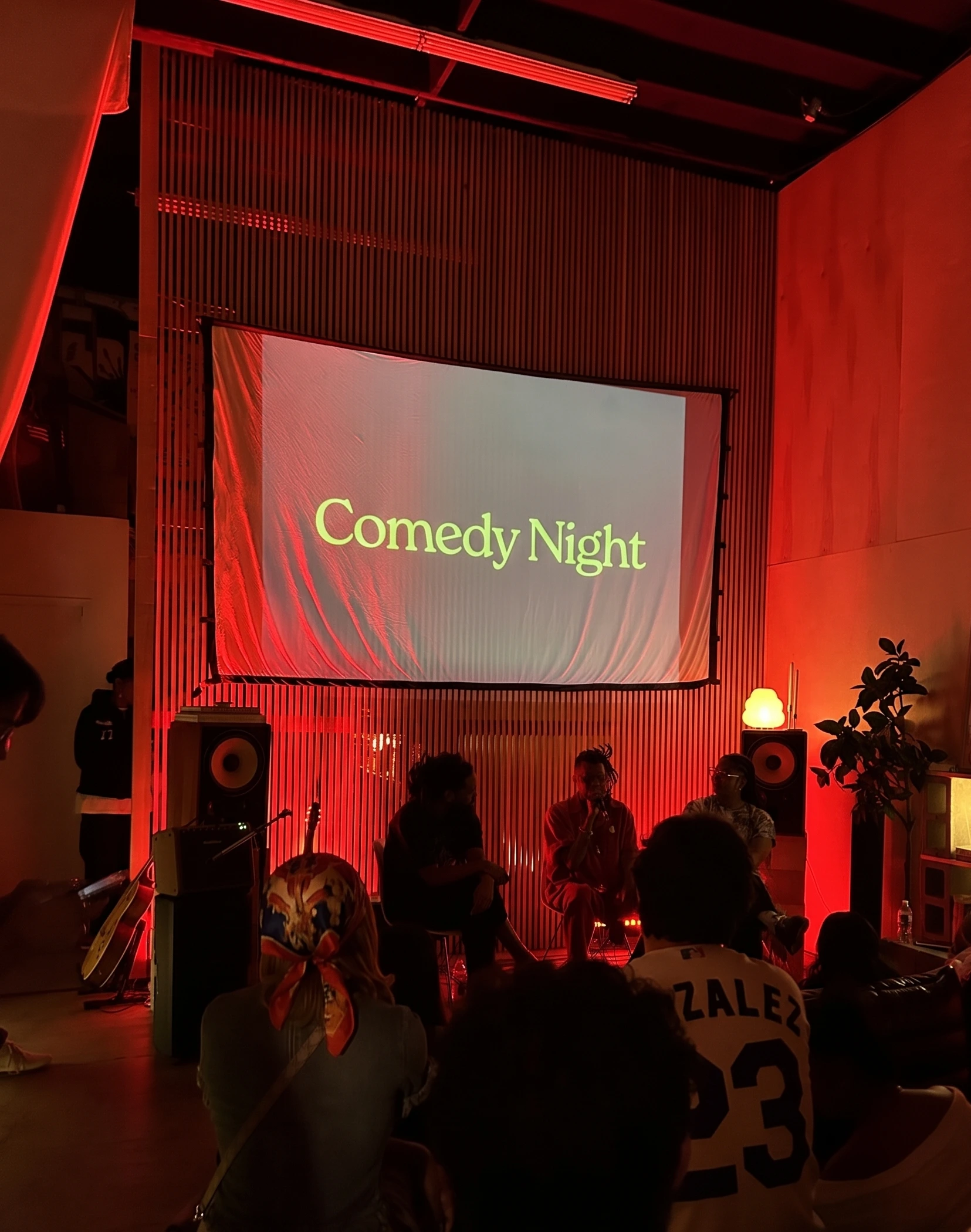 Comedy night with a projected screen and a warm-lit audience